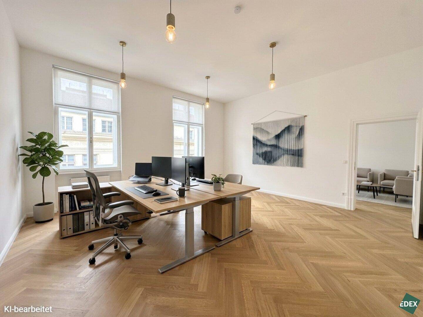 Helles Büro mit großem Schreibtisch für mehrere Arbeitsplätze, Fischgrätparkett und hohen Fenstern.