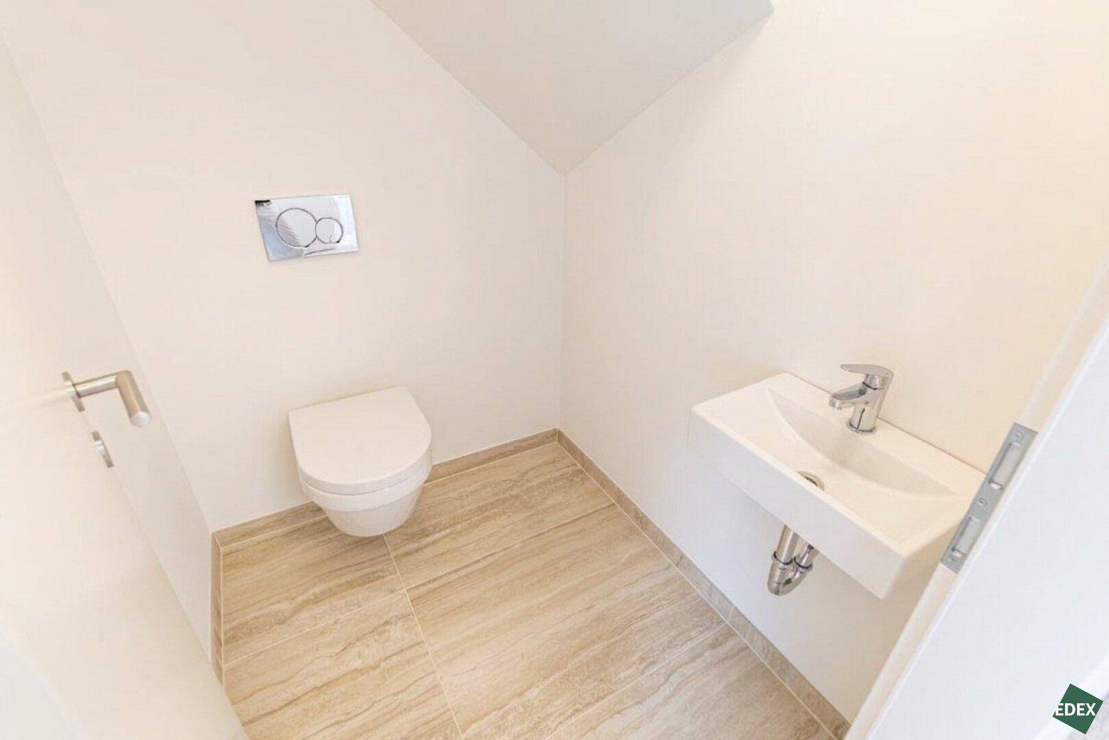 Modernes Gäste-WC mit Wand-WC, kleinem Waschbecken und Fliesenboden.