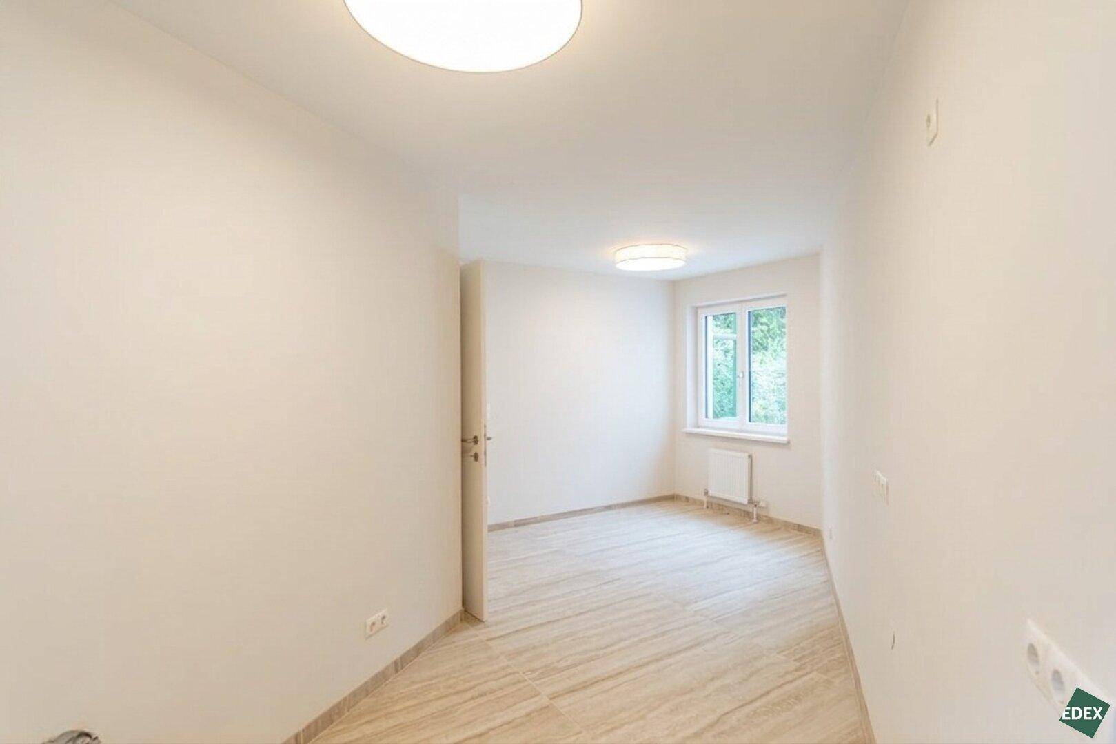 Heller, unmöblierter Raum mit Fliesenboden und Fenster, ideal für verschiedene Nutzungen.