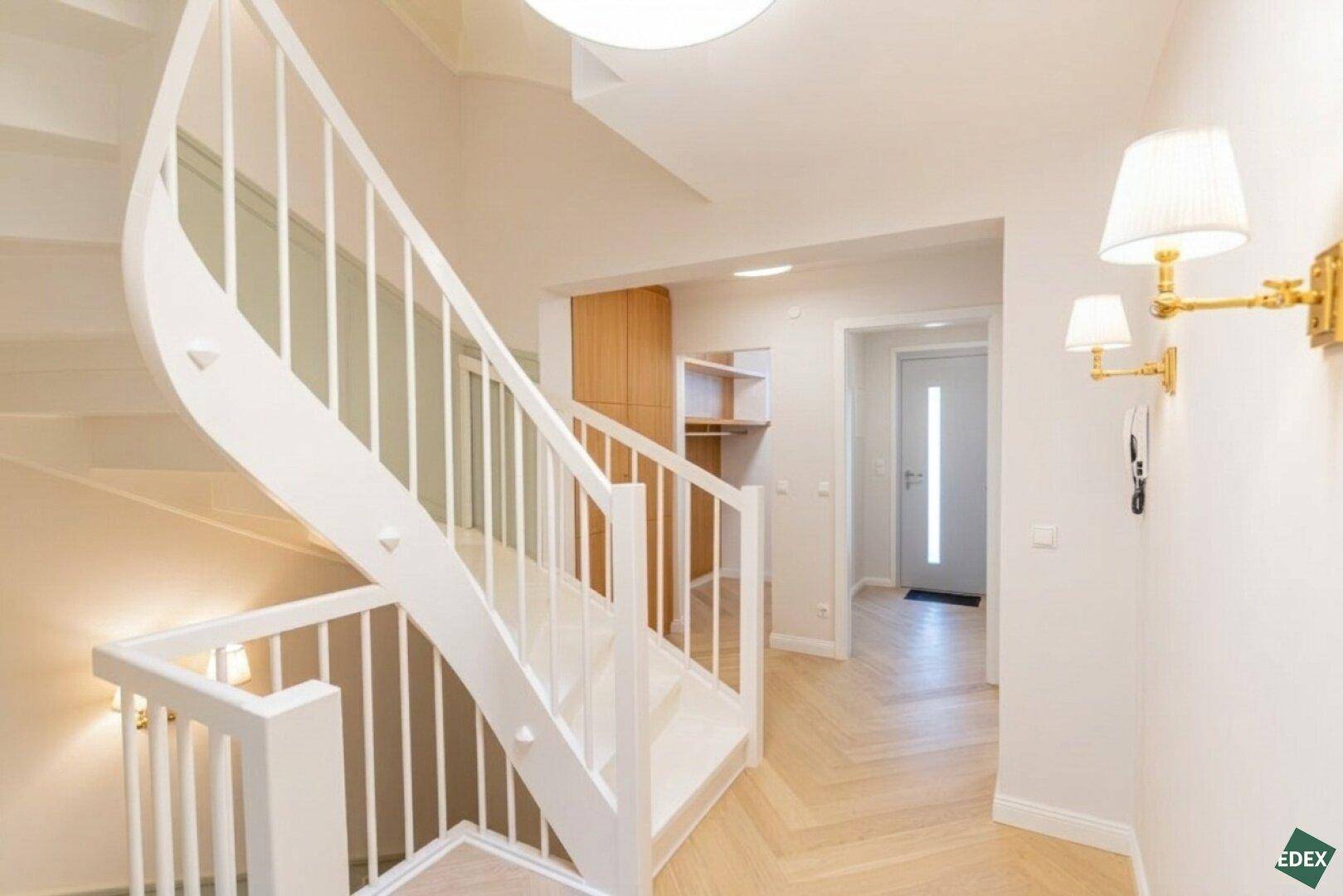 Geräumiger Flur mit geschwungener Treppe, Holzboden und integrierten Schränken.