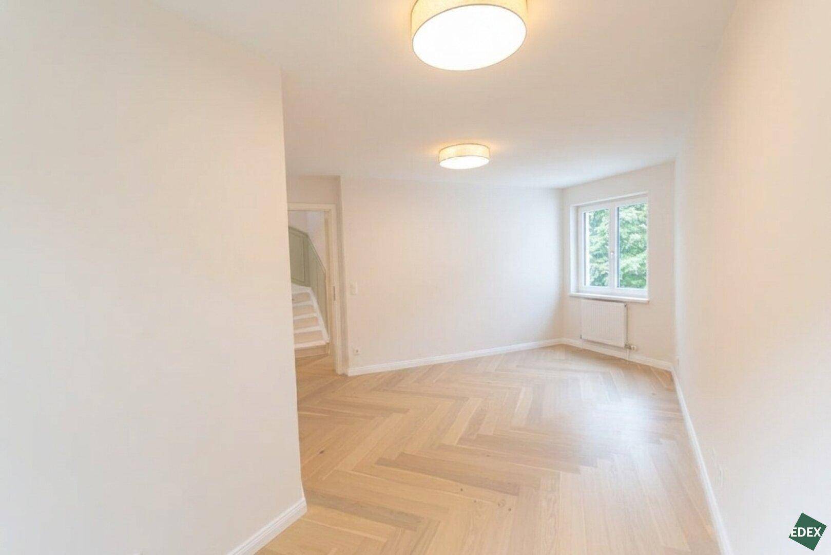 Geräumiger, unmöblierter Raum mit Holzboden und Fenster, vielseitig nutzbar.