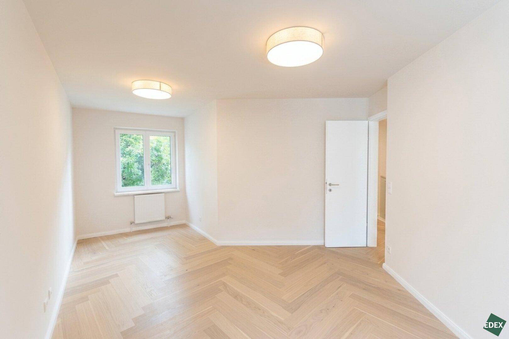 Helles, unmöbliertes Zimmer mit Holzboden und Fenster, ideal als Schlaf- oder Arbeitszimmer.