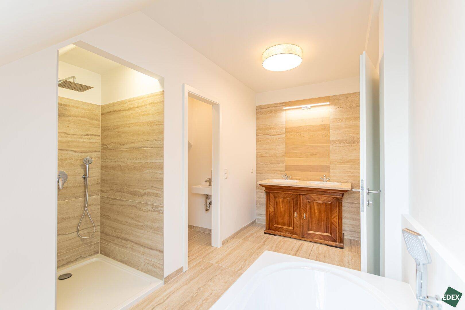 Geräumiges Badezimmer mit Badewanne, begehbarer Dusche und eleganten Fliesen.