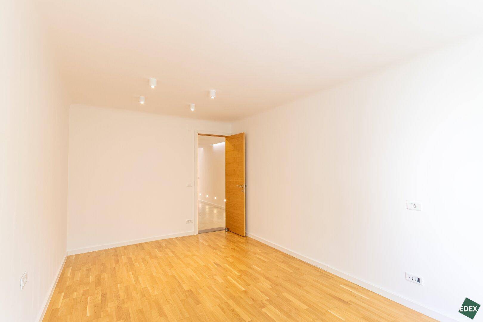 Geräumiges Schlafzimmer mit Parkettboden und schlichter, moderner Ästhetik.