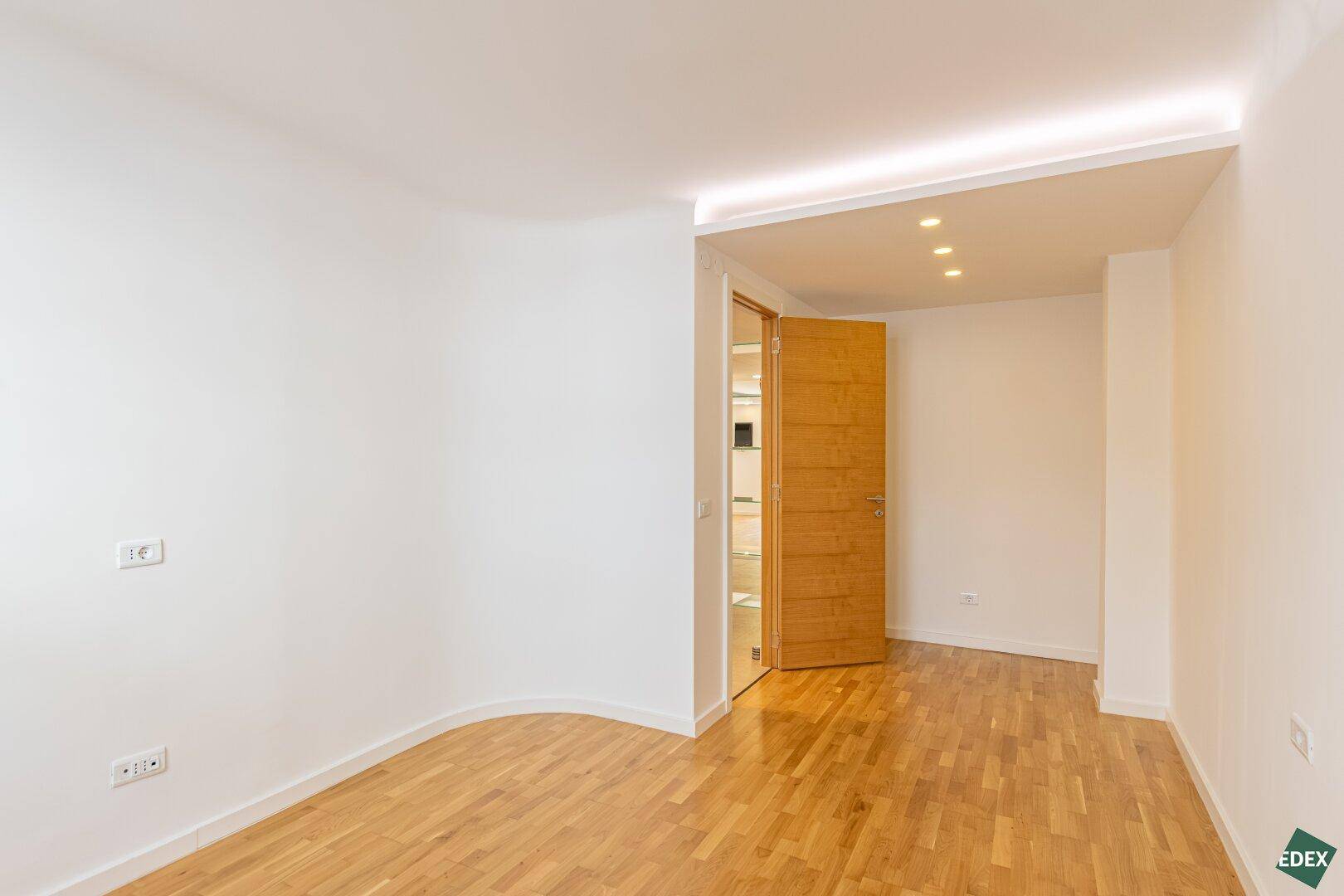 Geräumiges Schlafzimmer mit Parkettboden und indirekter Deckenbeleuchtung.