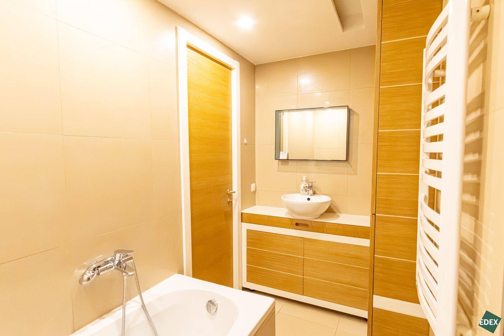 Modernes Badezimmer mit Badewanne, Waschbecken und beheiztem Handtuchhalter.