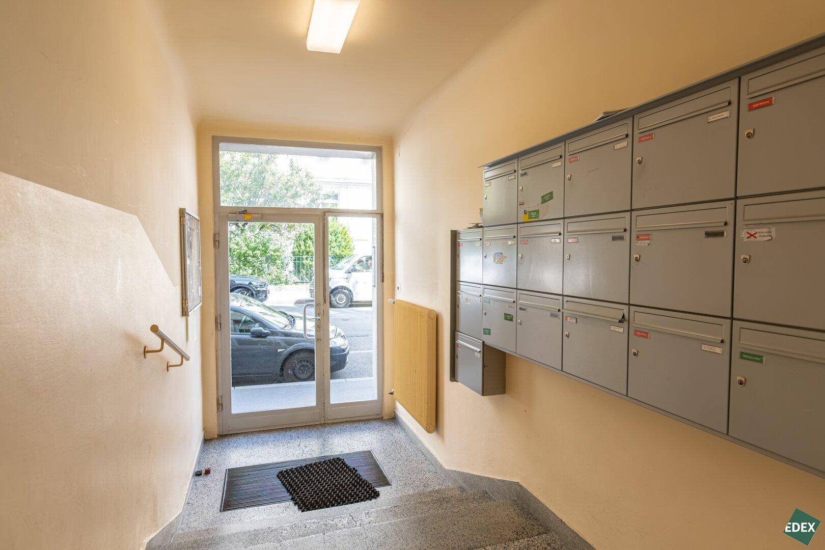 Eingangsbereich des Gebäudes mit Briefkästen und Zugang zur Straße.