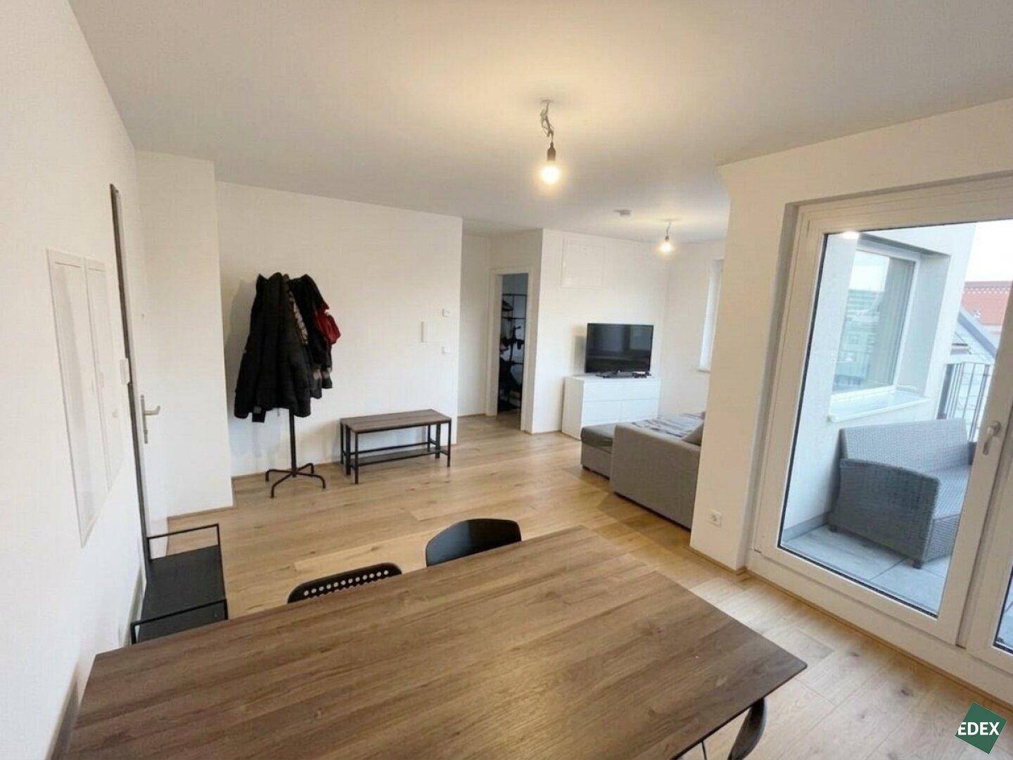 Eingangsbereich mit Garderobe und Blick in den offenen Wohnbereich mit Terrasse.