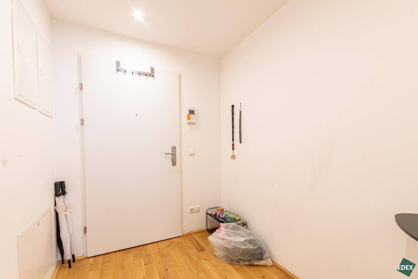Eingangsbereich der Wohnung mit heller Tür und ausreichend Platz für eine Garderobe.