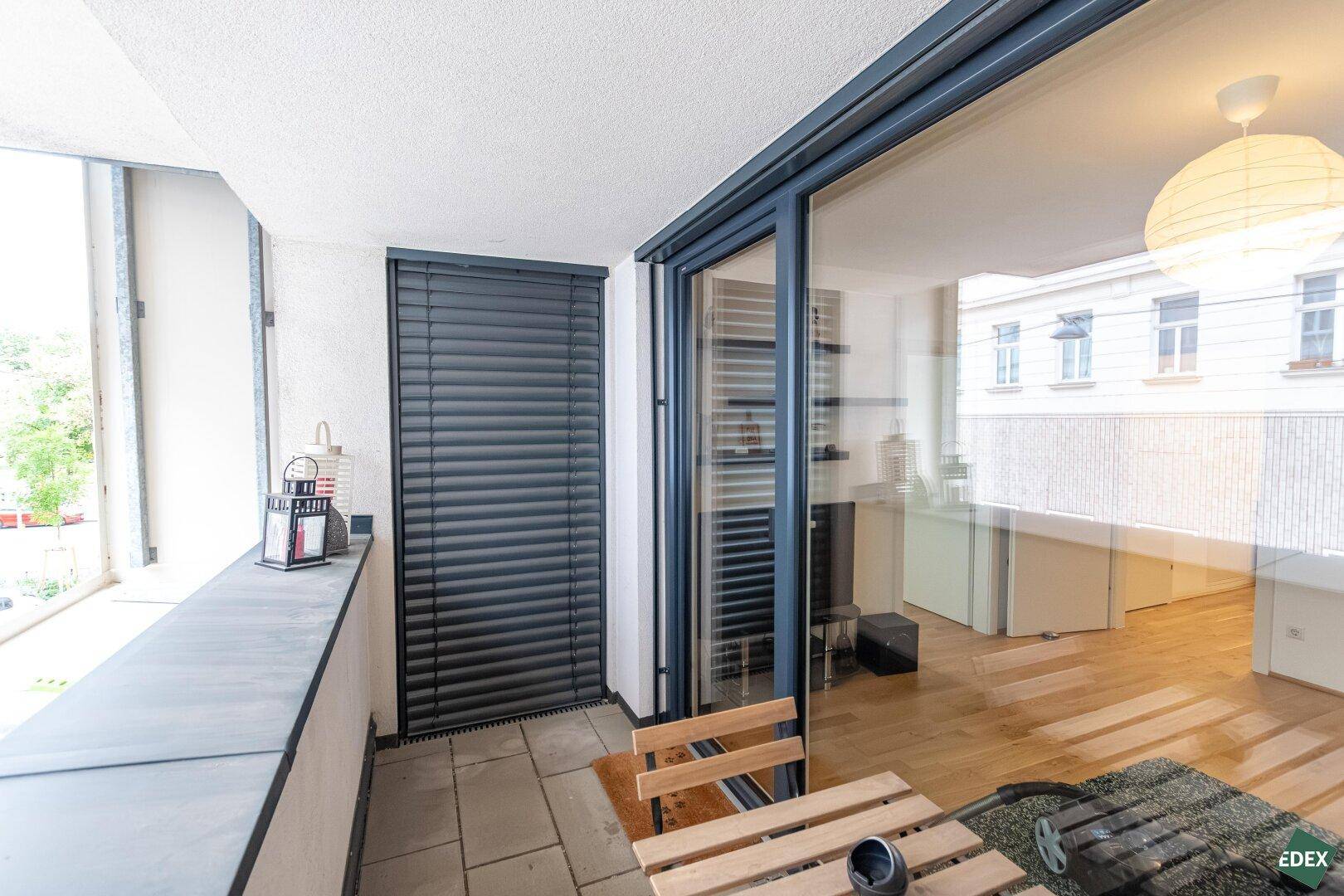 Balkon mit Außenjalousien und einem kleinen Holztisch, ideal für entspannte Stunden im Freien.
