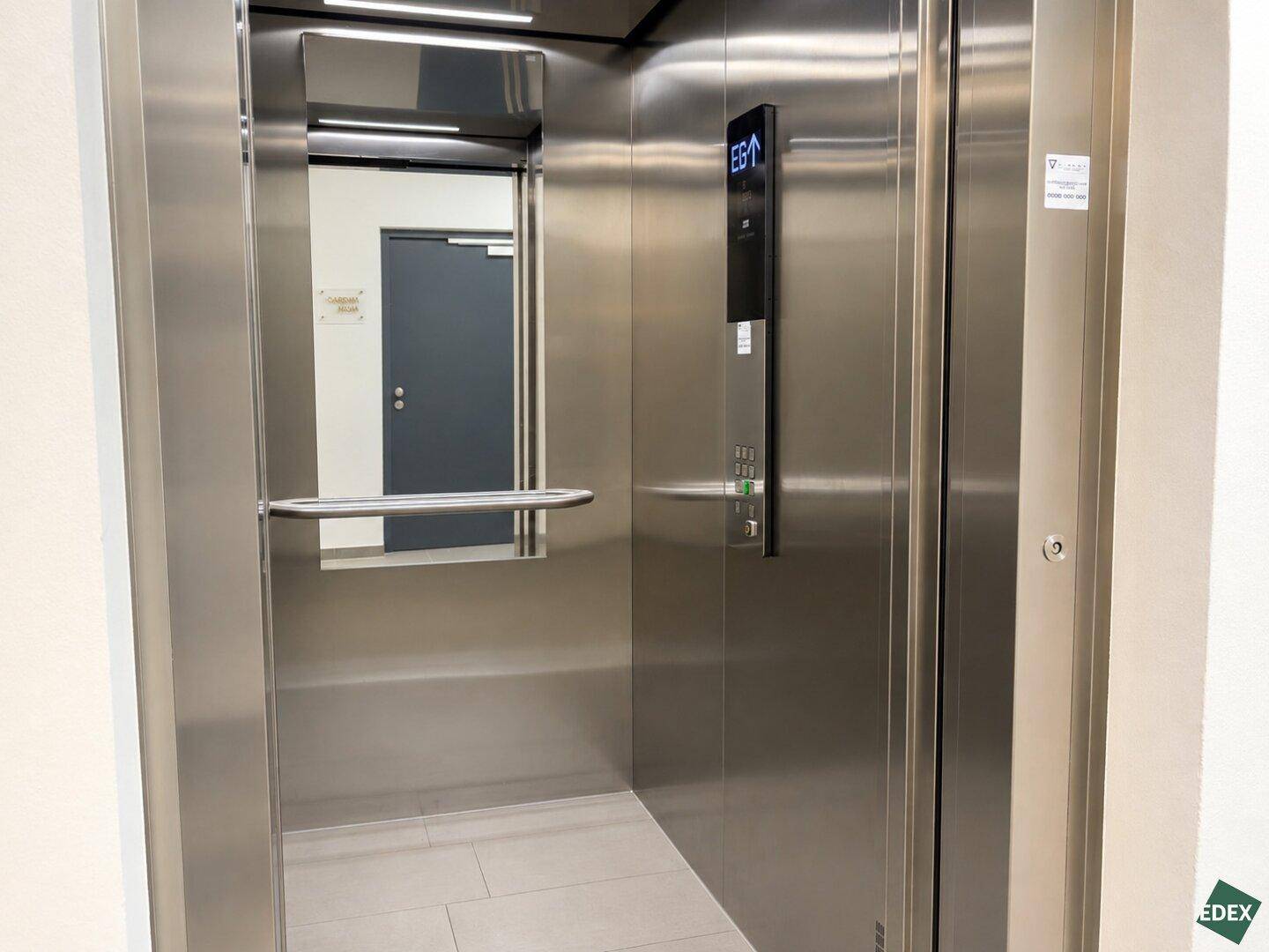 Moderner Aufzug mit Edelstahloberflächen und einem Spiegel im Inneren des Fahrstuhls.