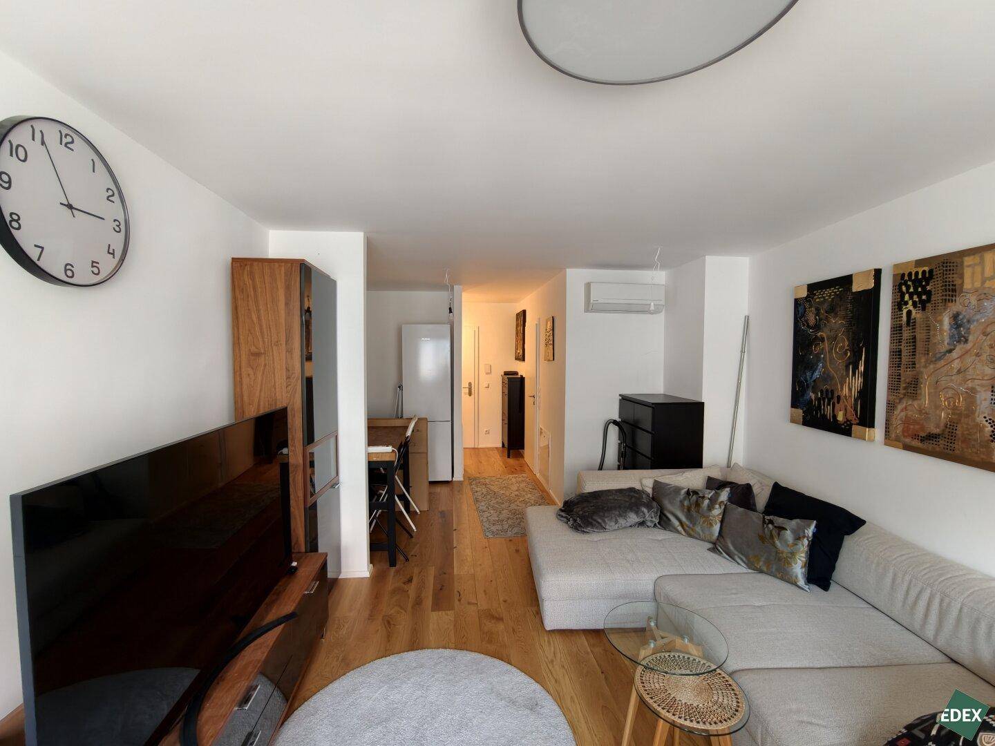 Offener Wohnbereich mit Holzboden, Sofa und Blick auf den Ess- und Küchenbereich.