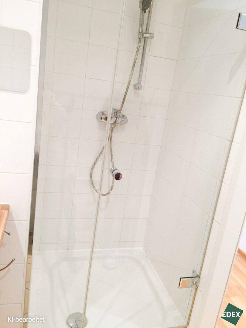 Helle Duschkabine mit Glasabtrennung und weißen Wandfliesen für ein frisches Badeerlebnis.