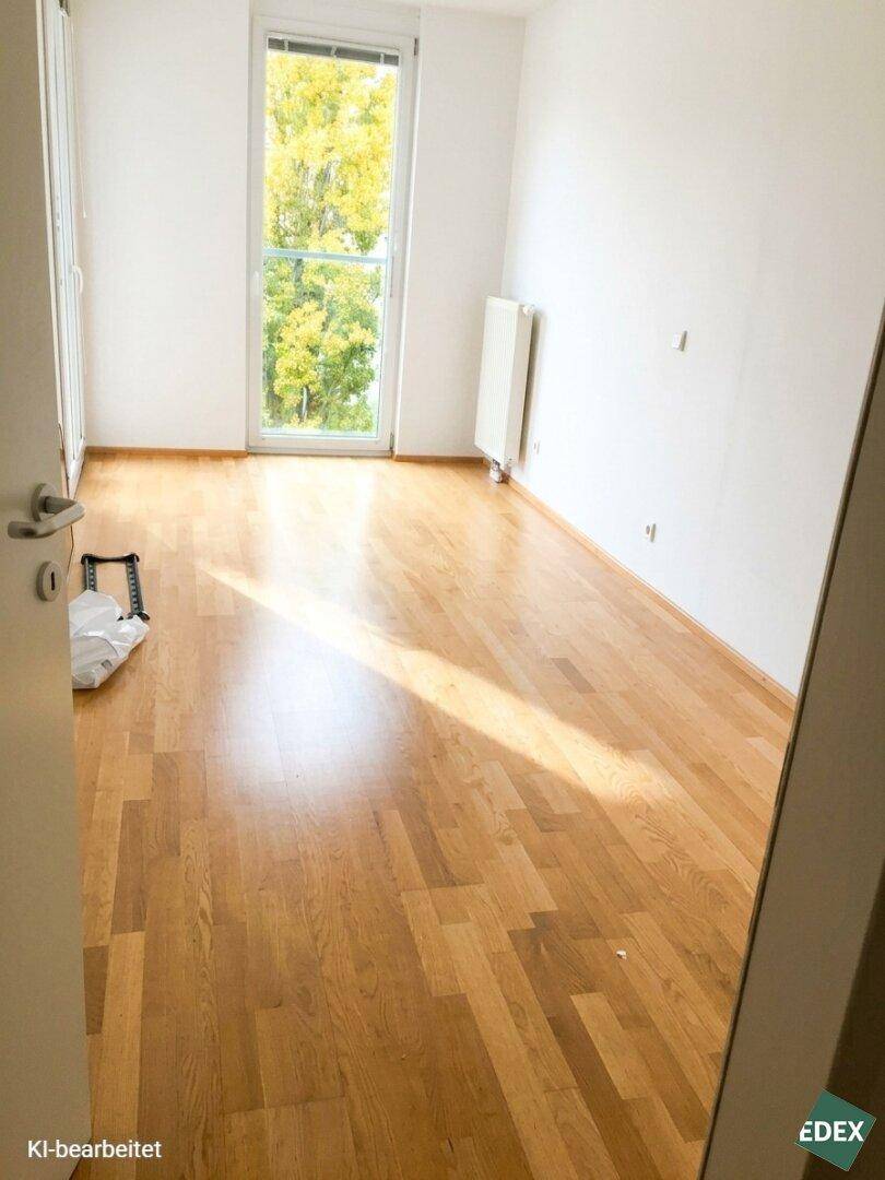 Freundliches Zimmer mit Parkettboden und Fensterblick ins Grüne, ideal als Schlaf- oder Arbeitszimmer.