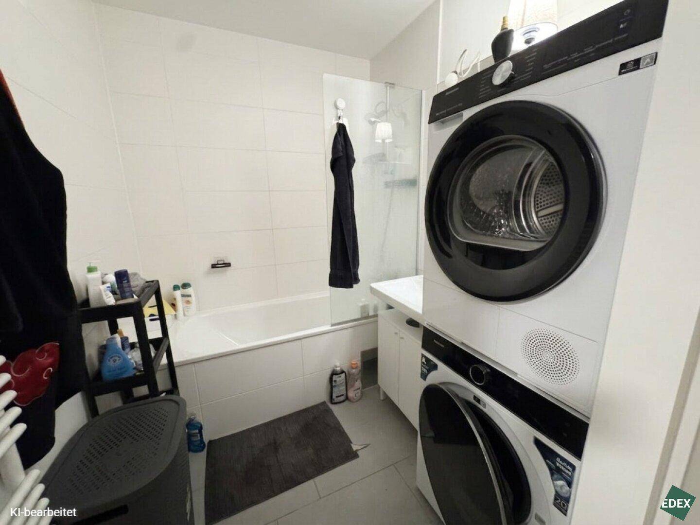 Modernes Badezimmer mit Badewanne, Duschabtrennung und integrierter Waschmaschine und Trockner.