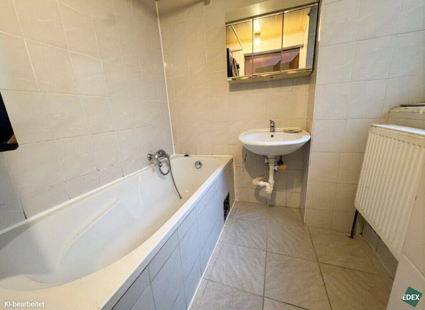 Gefliestes Badezimmer mit Badewanne, Waschbecken und Spiegelschrank.