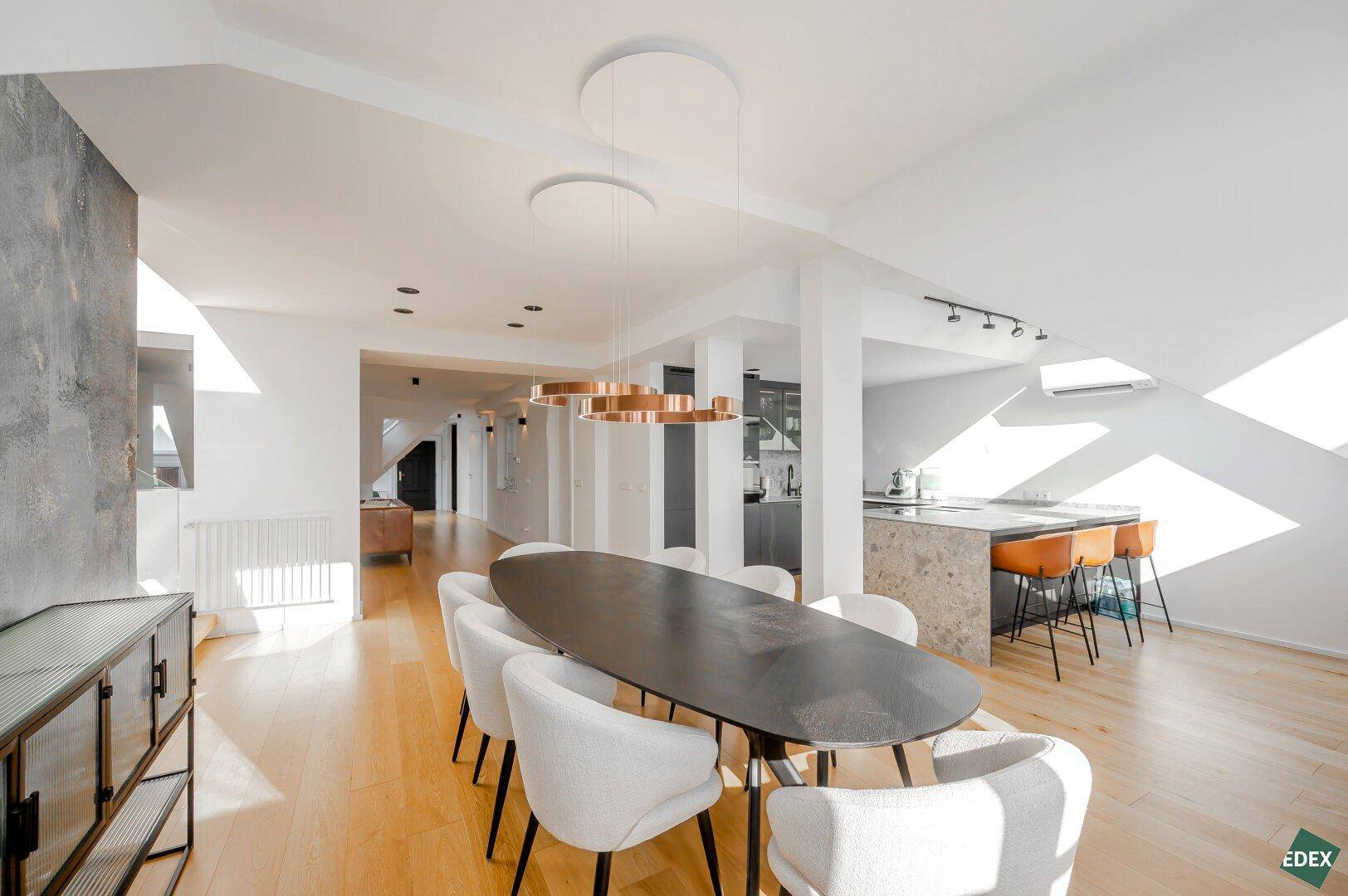 Heller Essbereich mit modernem Esstisch, Designerleuchten und Holzboden.