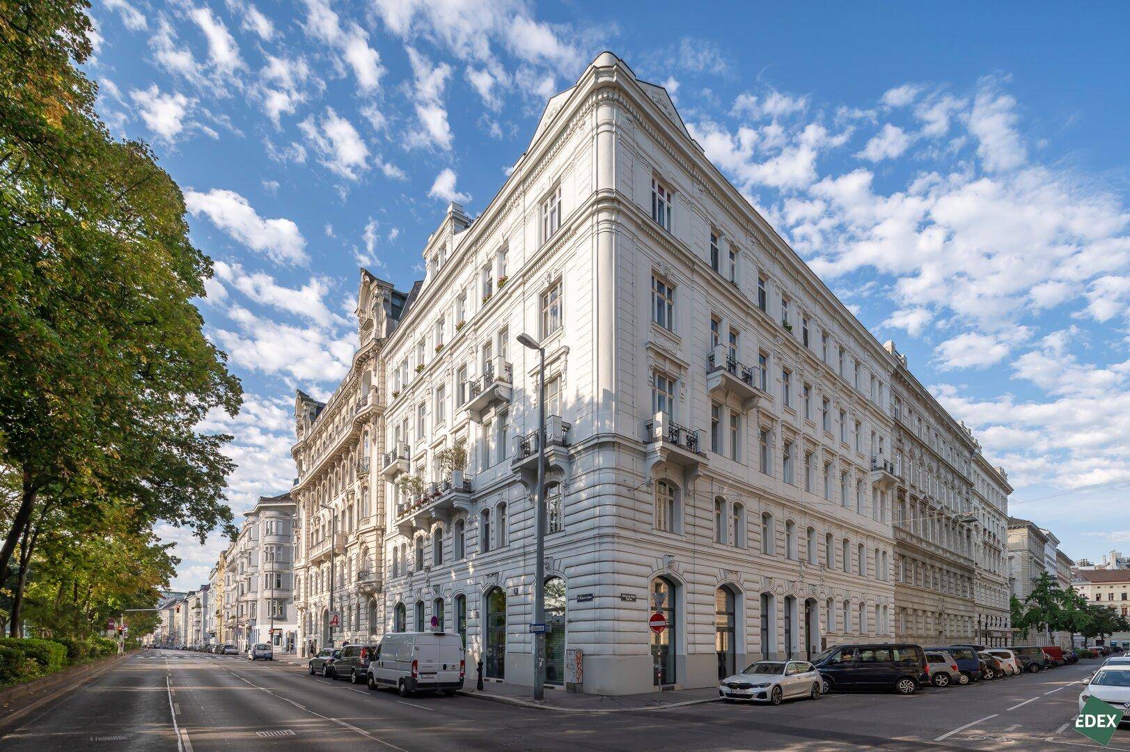 Elegantes Eckgebäude mit klassischer Architektur, vielen Fenstern und Balkonen in einer städtischen Umgebung.