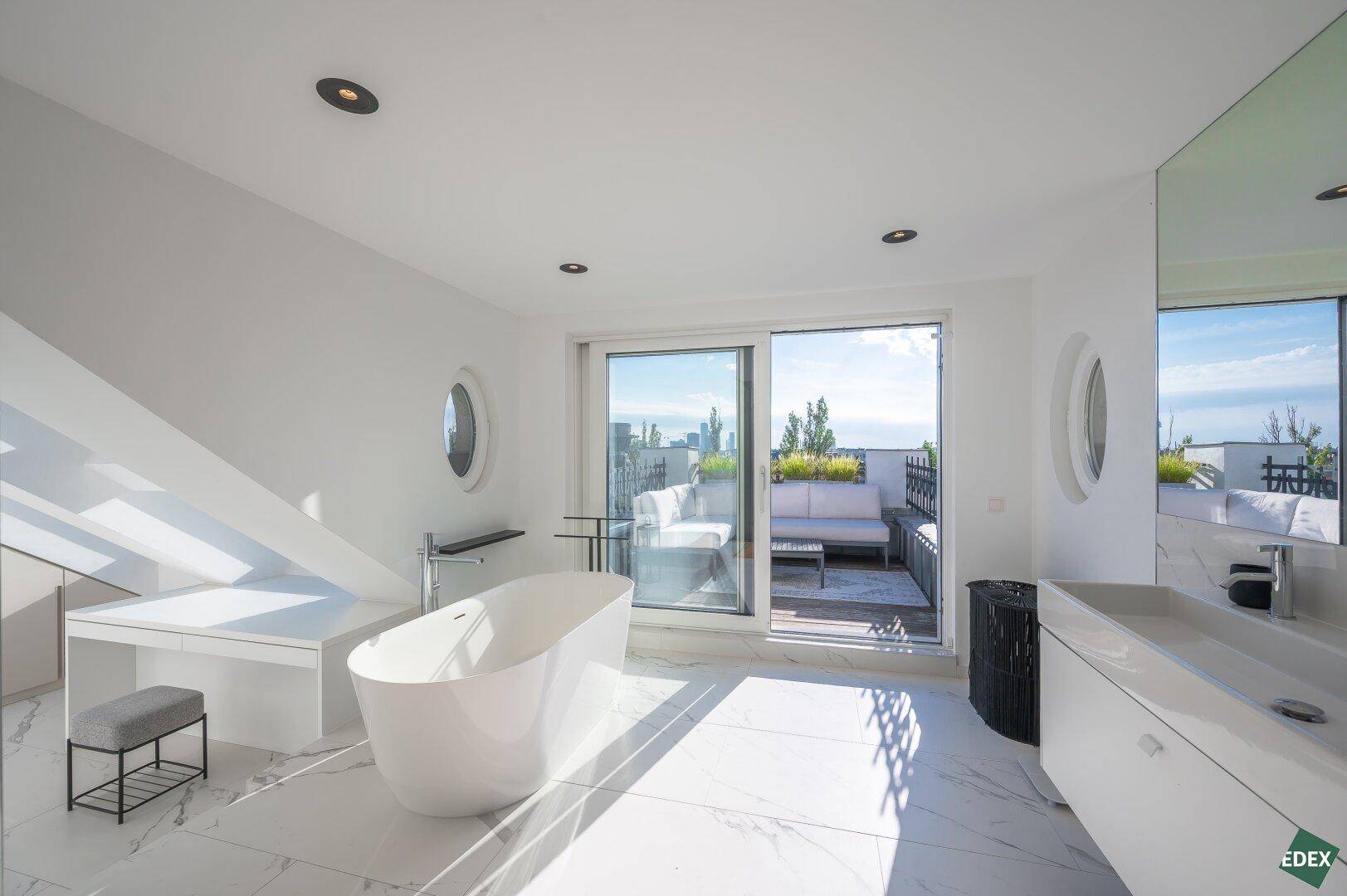 Helles, modernes Badezimmer mit freistehender Badewanne, Marmorfliesen und direktem Zugang zur Dachterrasse.