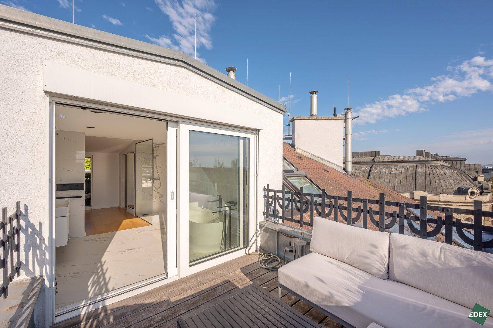 Gemütlicher Außenbereich auf der Terrasse mit Sitzgelegenheiten und Blick auf die Stadt, verbunden mit Innenräumen.
