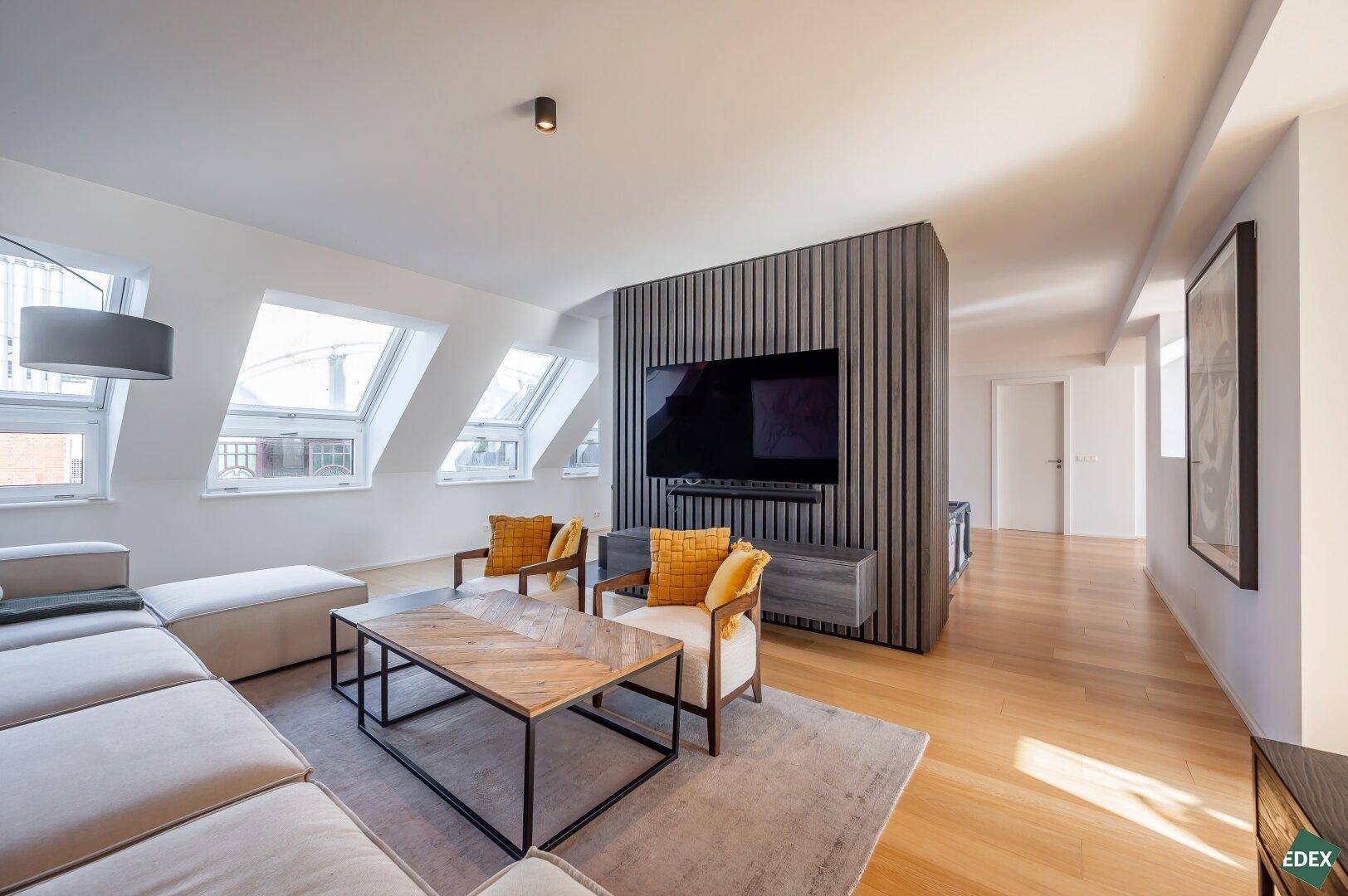 Modernes Wohnzimmer mit TV-Wand, bequemer Couch und Dachfenstern.