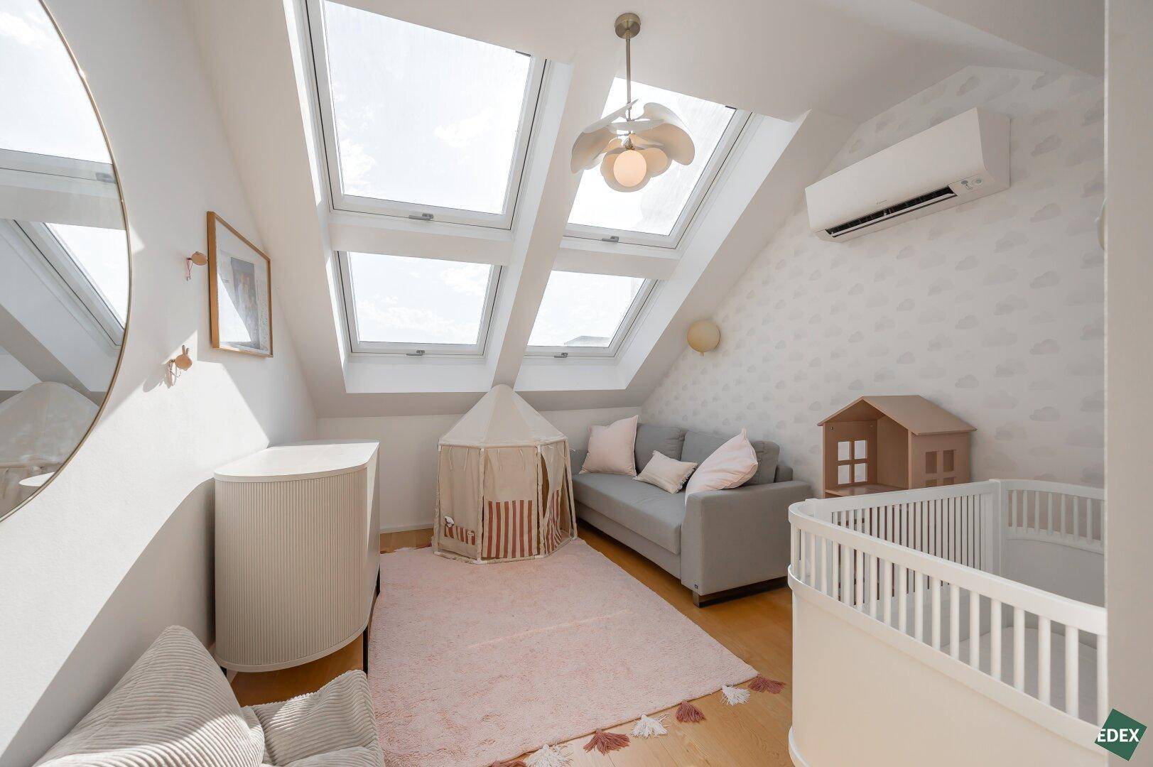 Freundliches Kinderzimmer mit viel Tageslicht durch große Dachfenster.