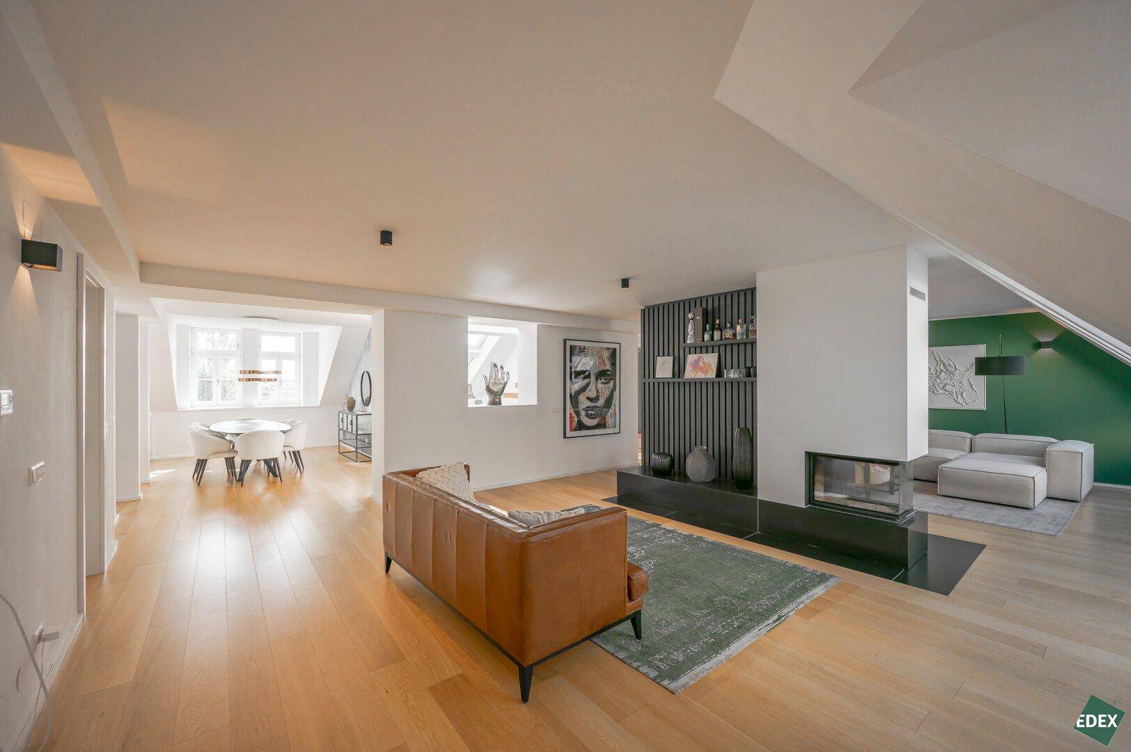Geräumiges Wohnzimmer mit Kamin, Holzboden und Blick auf den Essbereich.