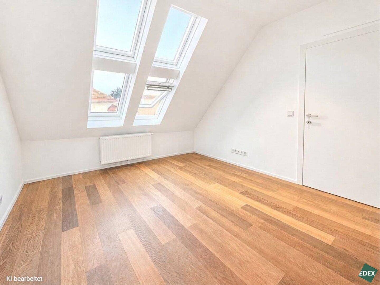 Helles Schlafzimmer im Dachgeschoss mit Holzboden, Heizkörper und zwei Dachfenstern.
