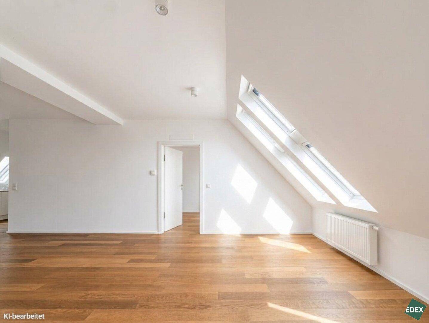 Geräumiges Dachgeschosszimmer mit Holzboden, schrägen Wänden und hellen Dachfenstern.