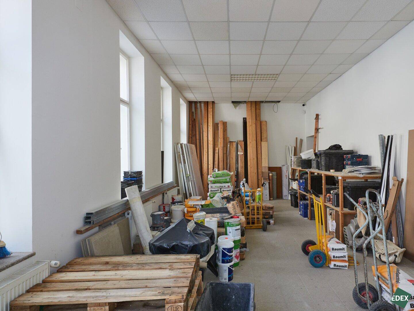 Weiterer Blick in den Lagerraum mit gestapelten Holzbrettern und verschiedenen Baumaterialien.