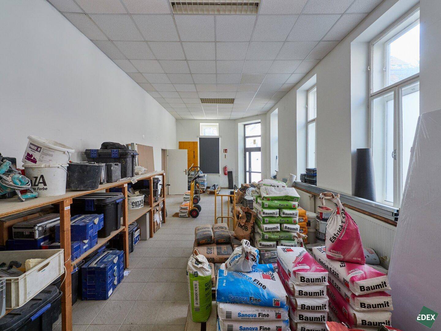 Großer Lagerraum mit Baumaterialien, Säcken und Werkzeugen, bereit für Bauarbeiten.