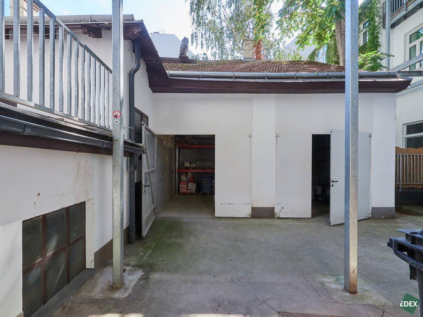 Weiterer Blick auf den Hinterhof mit Garagengebäude und offenem Zugang zu Lagerräumen.