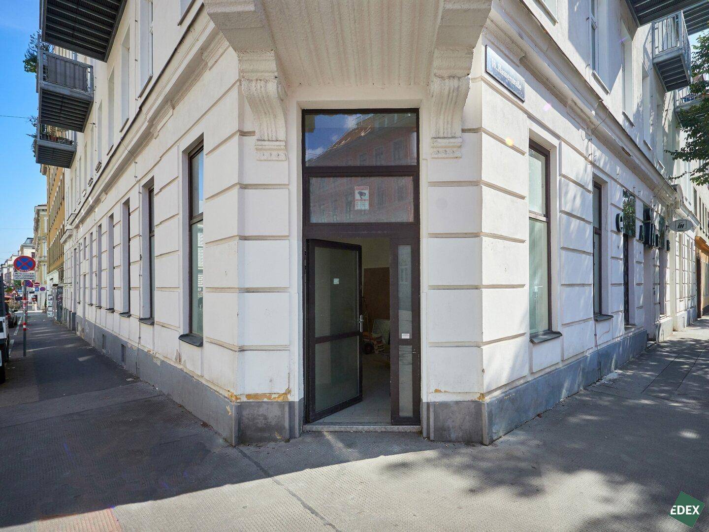 Eckgebäude mit hellem Putz und einem einladenden Eingangsbereich an einer städtischen Straße.