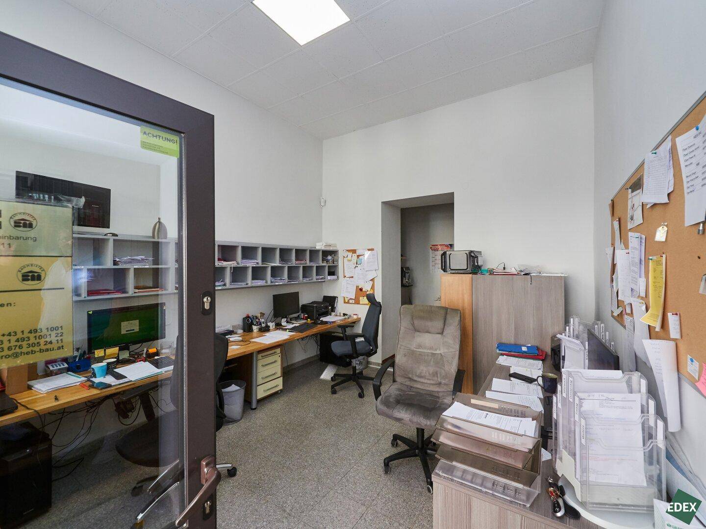 Funktionales Büro mit mehreren Arbeitsplätzen, Schreibtischen und Ablagesystemen für den täglichen Betrieb.