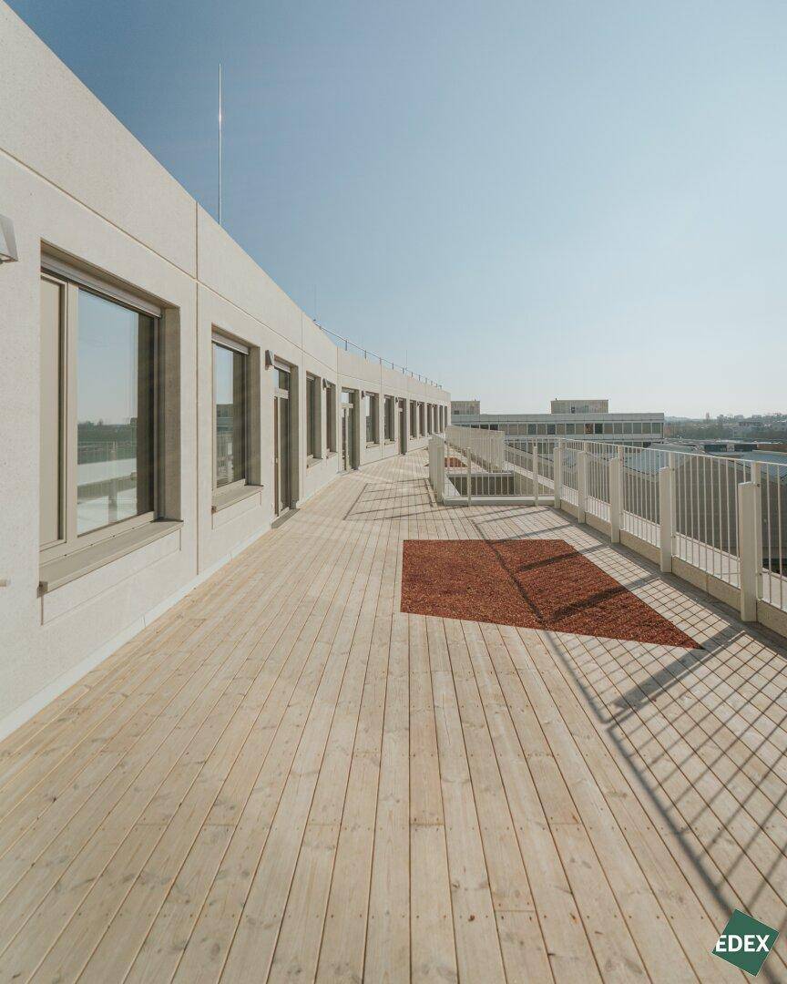 Weitläufige Dachterrasse mit Holzplankenboden und Metallgeländer, ideal für Entspannung im Freien.