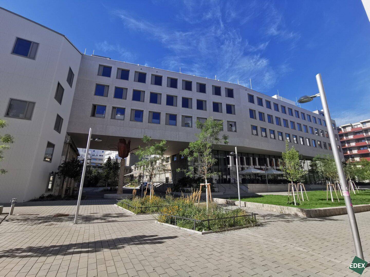 Weitläufige Außenansicht eines modernen Gebäudes mit großen Fenstern und gepflegten Grünanlagen.