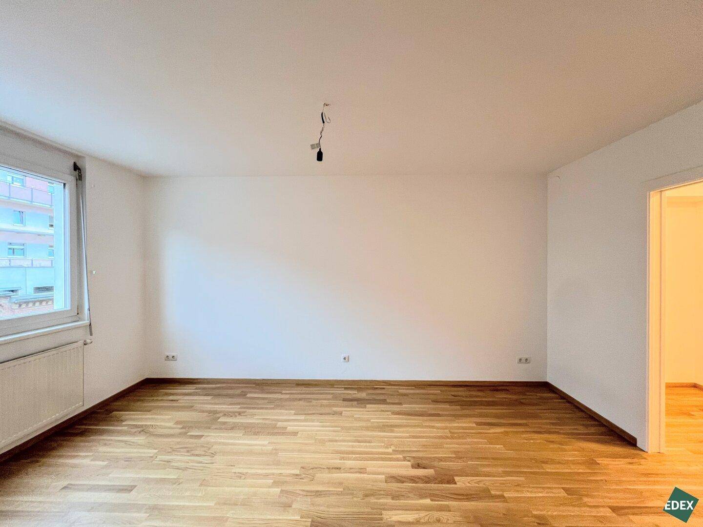 Geräumiges, unmöbliertes Zimmer mit Parkettboden und einem Fenster, das viel Licht spendet.