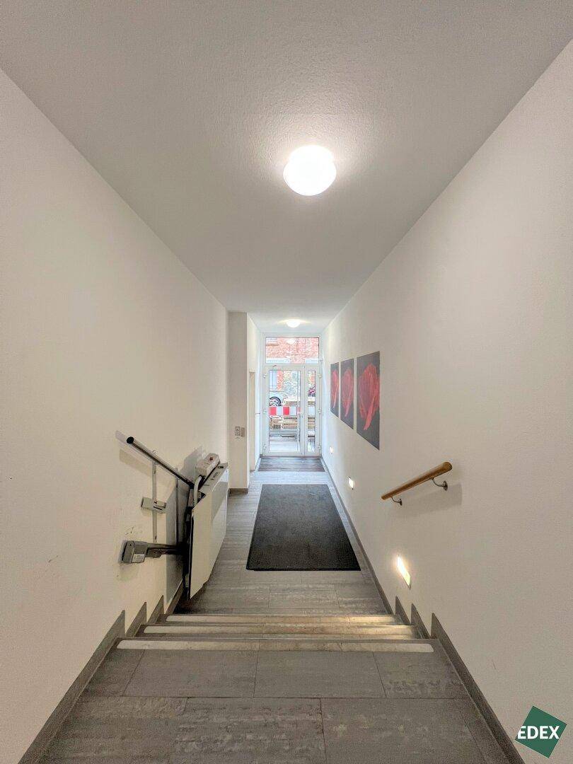 Treppenhaus mit Handläufen und einem Treppenlift, der Barrierefreiheit gewährleistet.