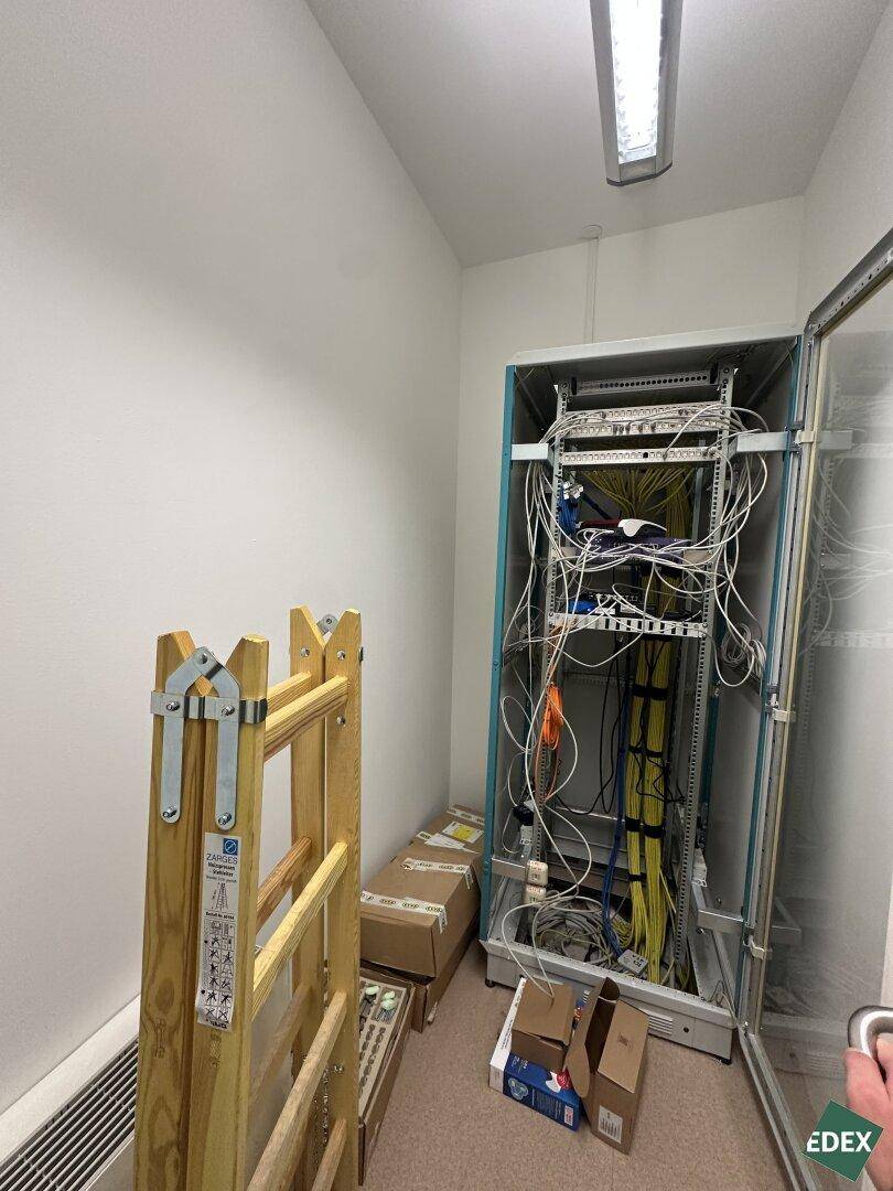 Serverraum mit offenem Rack, Verkabelung und einem Klappgerüst an der Wand.