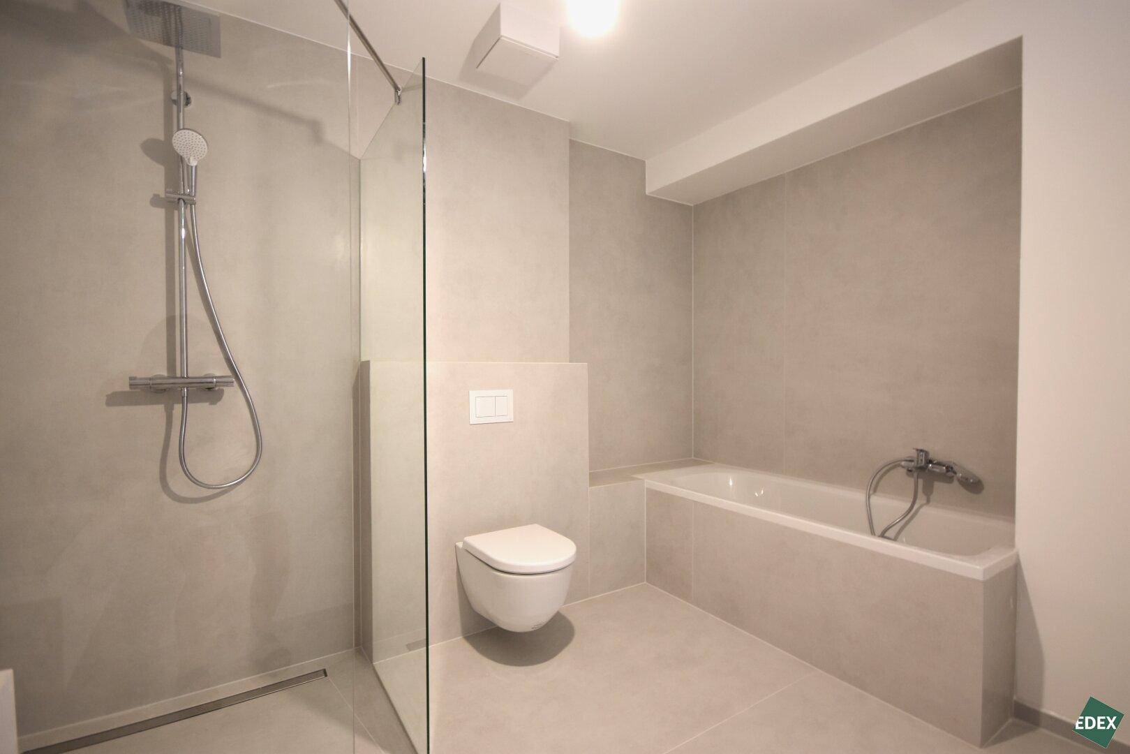 Modernes Badezimmer mit Badewanne, Dusche und Wand-WC.