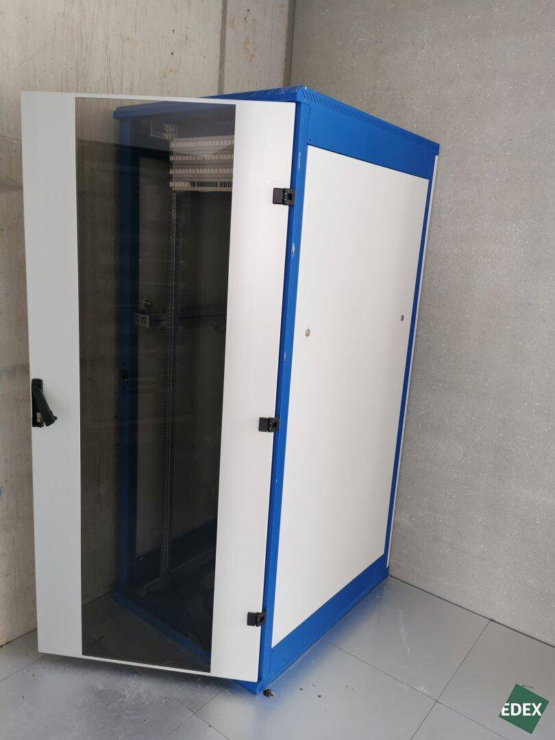 Blau-weißer Serverschrank in einem Raum mit Sichtbetonwänden, bereit für technische Installationen.