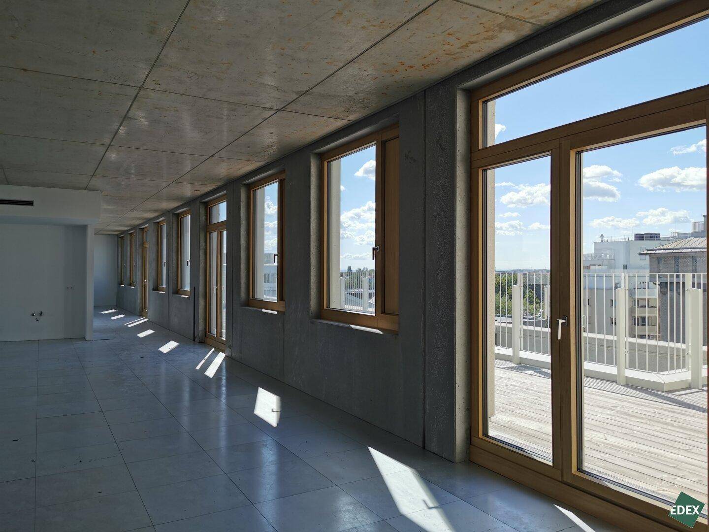 Heller Büroraum mit direktem Zugang zu einer Außenterrasse und weitem Blick über die Stadt.