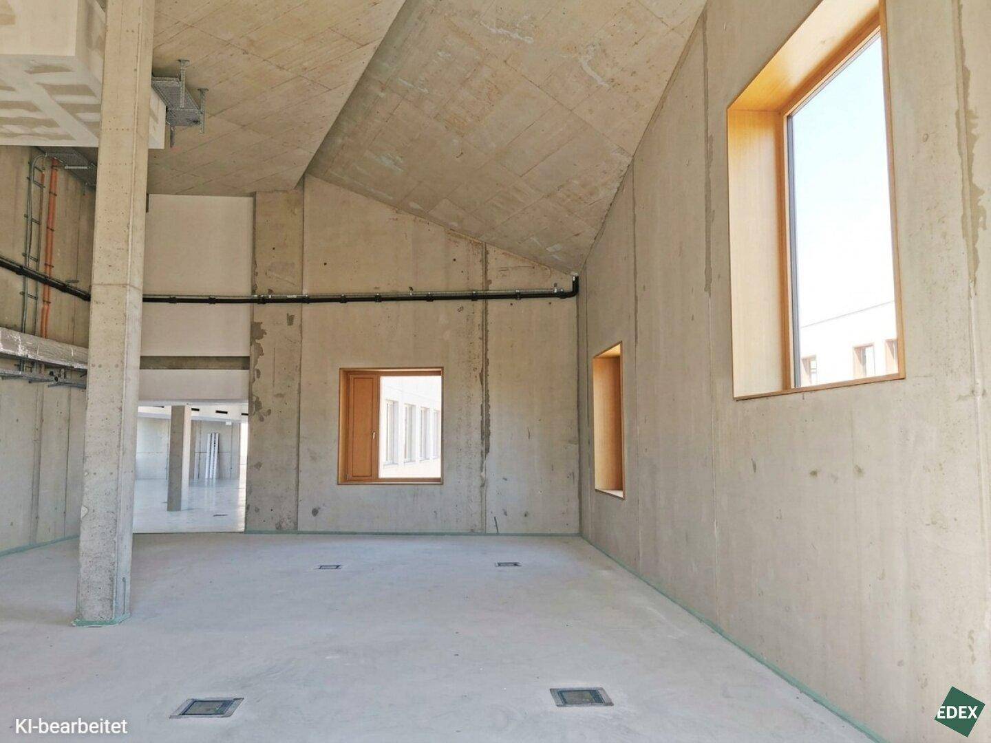 Unfertiger Raum mit schrägen Betonwänden und -decke, bietet Potenzial für individuelle Gestaltung.