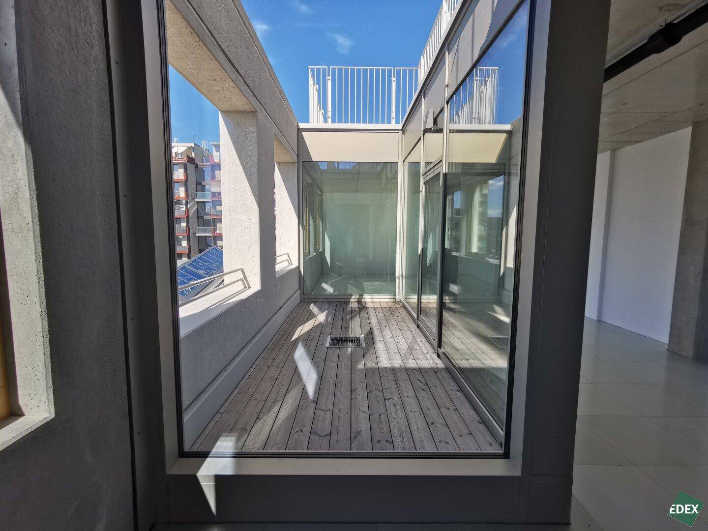 Helle Loggia mit Holzboden und Glasfronten, bietet einen geschützten Außenbereich mit viel Tageslicht.