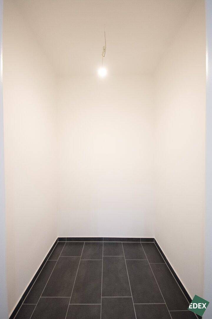 Kleiner Abstellraum mit dunklen Fliesen und weißen Wänden, ideal für zusätzlichen Stauraum.