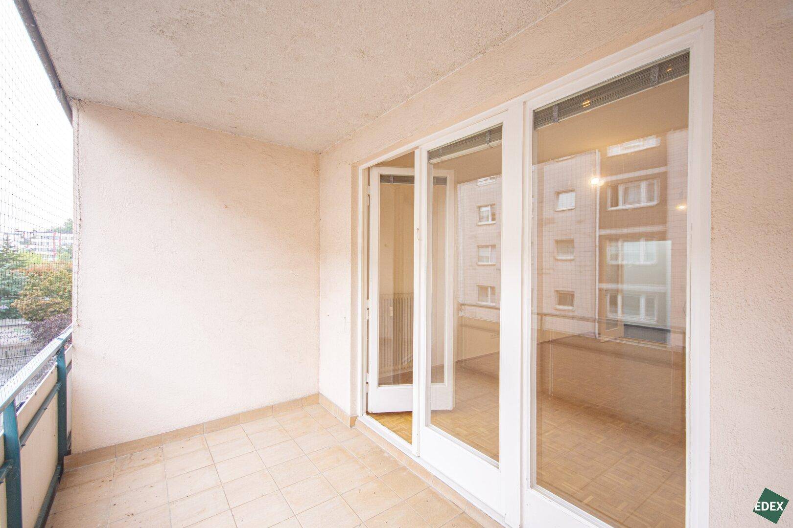 Überdachter Balkon mit Fliesenboden und Blick auf die umliegenden Gebäude.
