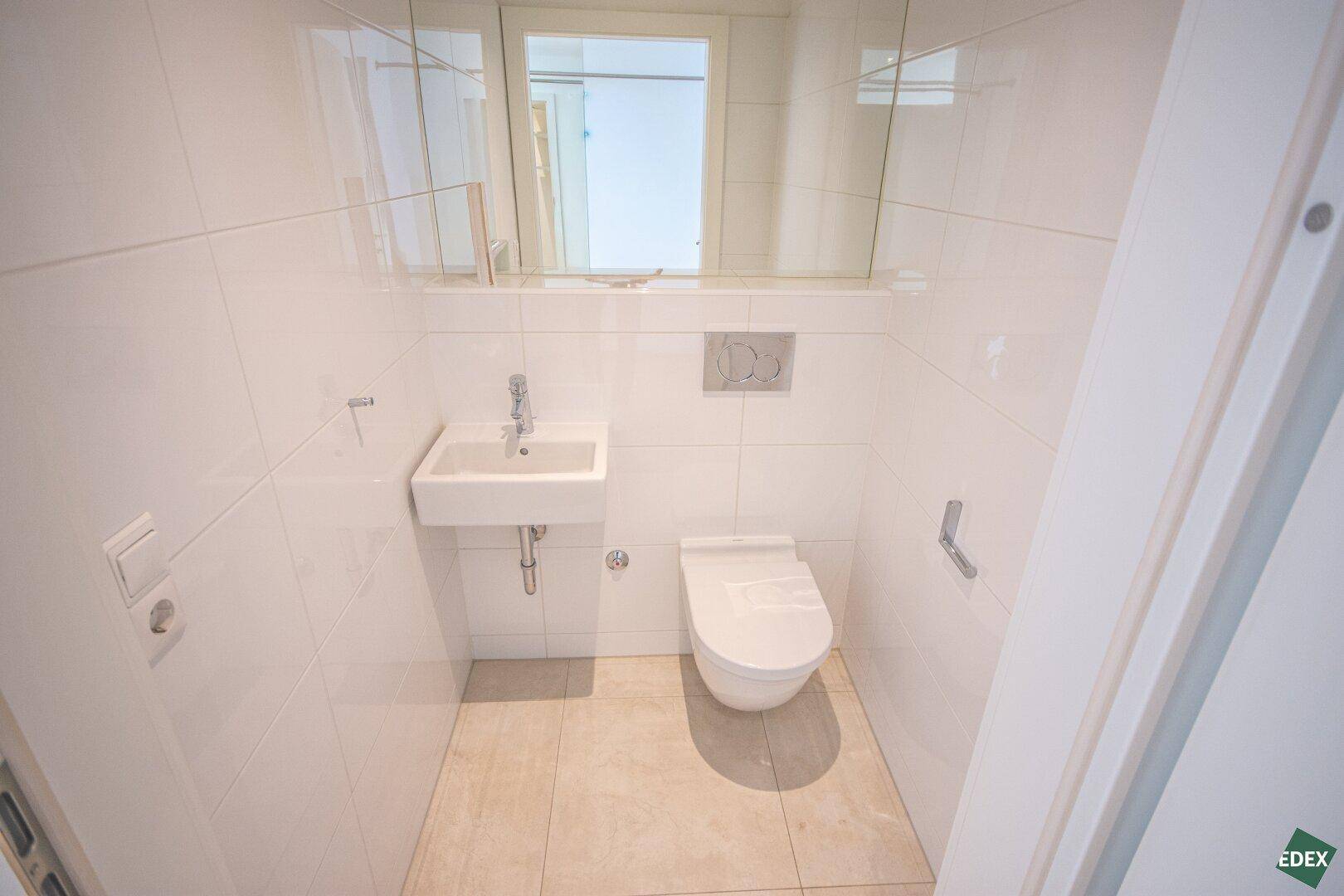 Kleines Gäste-WC mit wandhängendem WC, Waschbecken und Spiegelschrank, praktisch und hell.