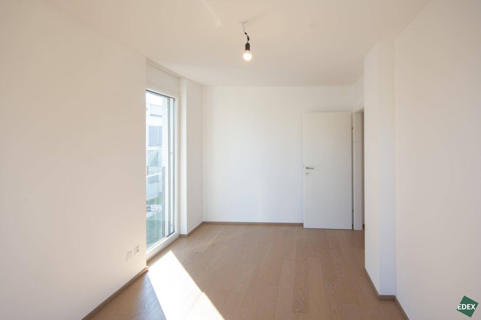 Geräumiges Zimmer mit Holzboden und weiß gestrichenen Wänden, ideal als Schlaf- oder Arbeitszimmer.