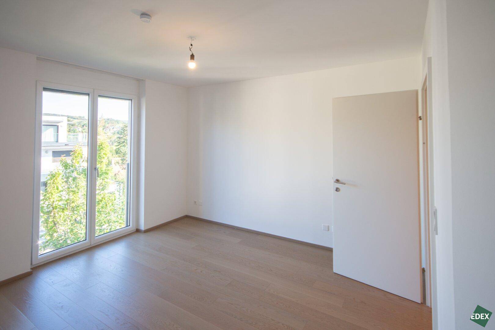 Lichtdurchflutetes Zimmer mit Holzboden und Blick ins Grüne, perfekt für Ruhe und Entspannung.