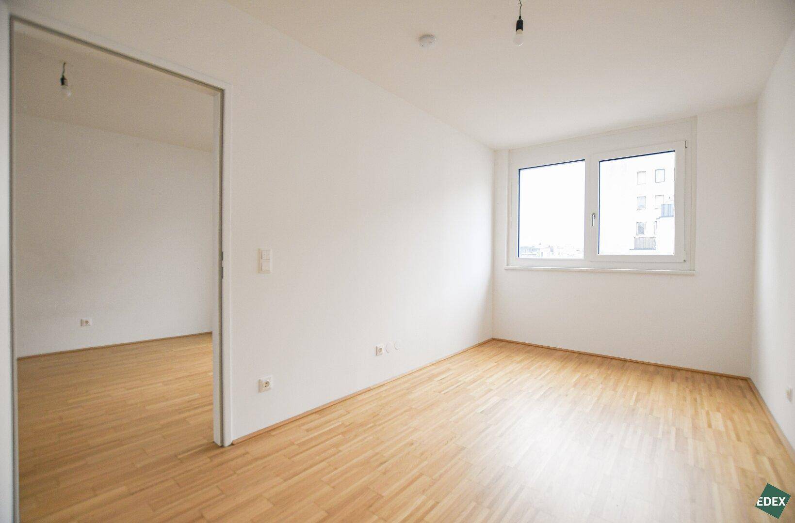 Geräumiges, helles Zimmer mit Parkettboden und großem Fenster, vielseitig nutzbar.